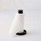 Cream tear-off napkins with gray stitching in a black metal napkin holder.