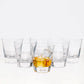 Set of 6 clear crystal whiskey glasses, one with amber liquid and ice.