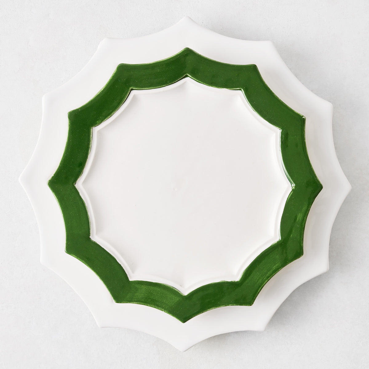 Stella ceramic salad plate with a white center and dark green scalloped edge on a white background.