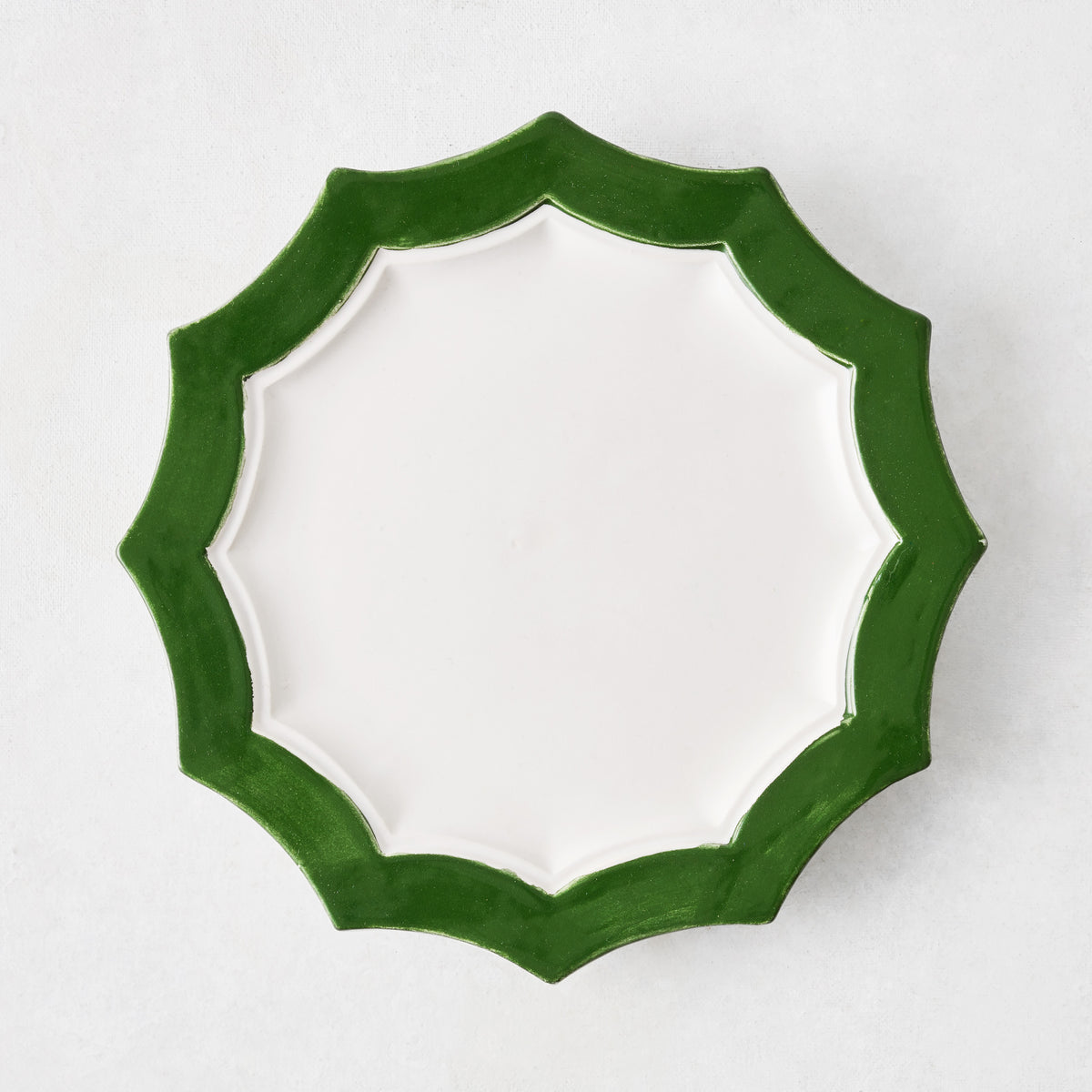 Stella ceramic salad plate with a white center and a dark green scalloped rim on a white background.