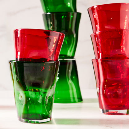 Stacked dark green and red Henri mouth-blown glass tumblers with unique imperfections.
