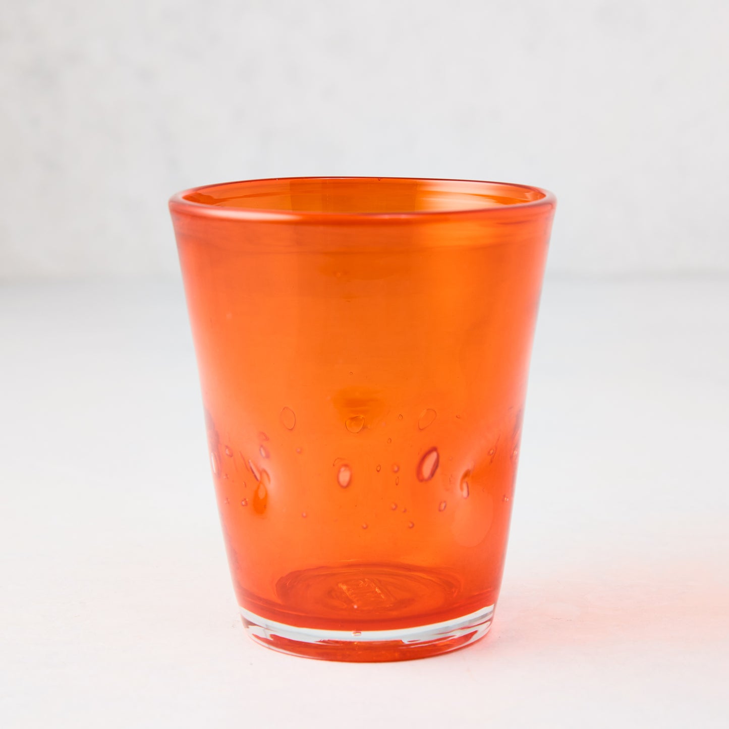 Dark orange Henri mouth-blown glass, 8 oz, with unique air bubbles and slight asymmetry.