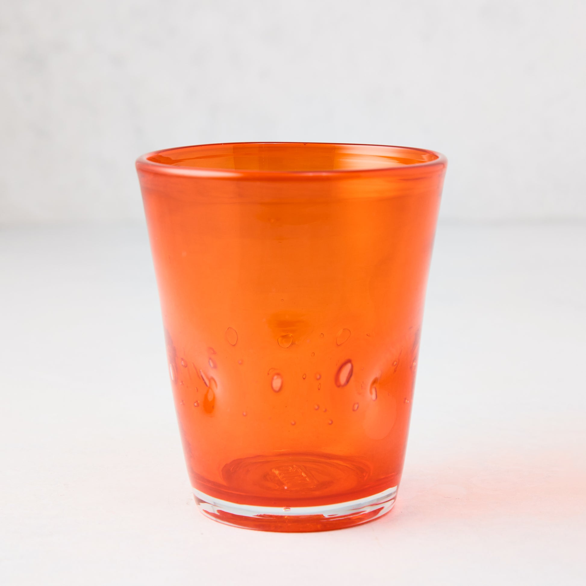 Dark orange Henri mouth-blown glass, 8 oz, with unique air bubbles and slight asymmetry.