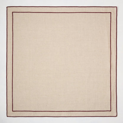 Beige natural cotton napkin with dark plum double-line embroidered border.