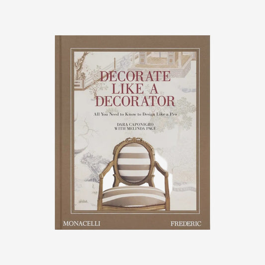 Hardcover book "Decorate Like a Decorator" with a brown spine and a cover featuring a striped chair against a scenic wallpaper.