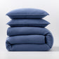 Stacked denim blue European washed linen duvet cover and two matching pillow shams on a white background.