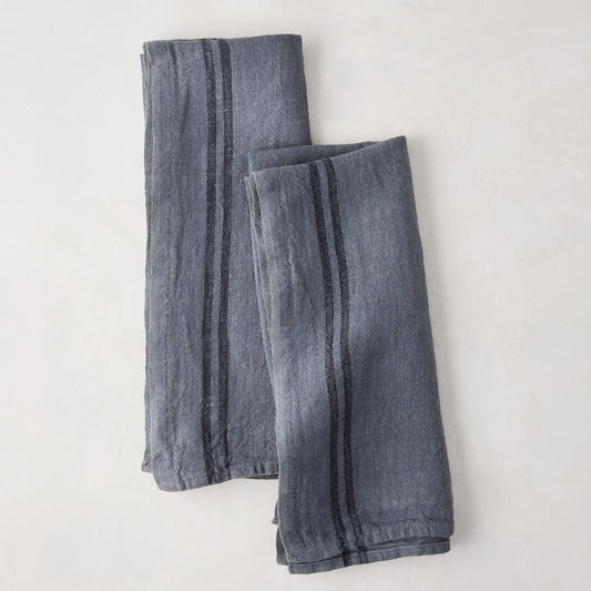 Set of 2 denim blue striped linen tea towels, folded on a white surface.
