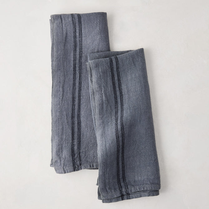 Set of 2 denim blue striped linen tea towels, folded on a white surface.