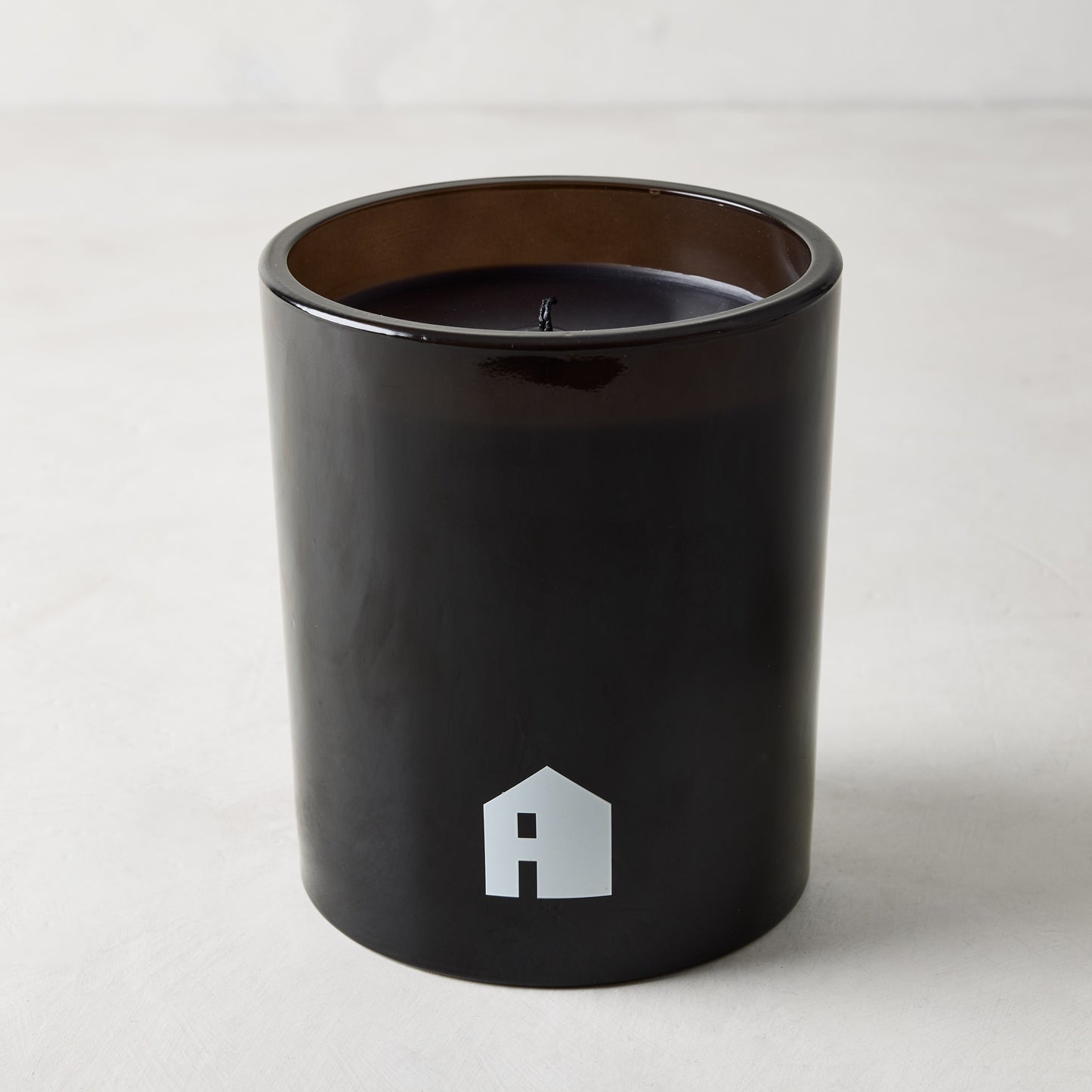 Diane Keaton "HOUSE" scented candle in a sleek black glass vessel with a white house logo.