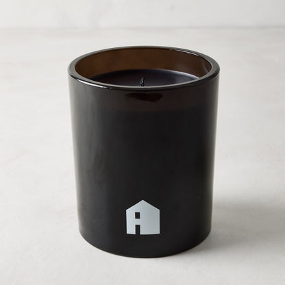 Diane Keaton "HOUSE" scented candle in a sleek black glass vessel with a white house logo.