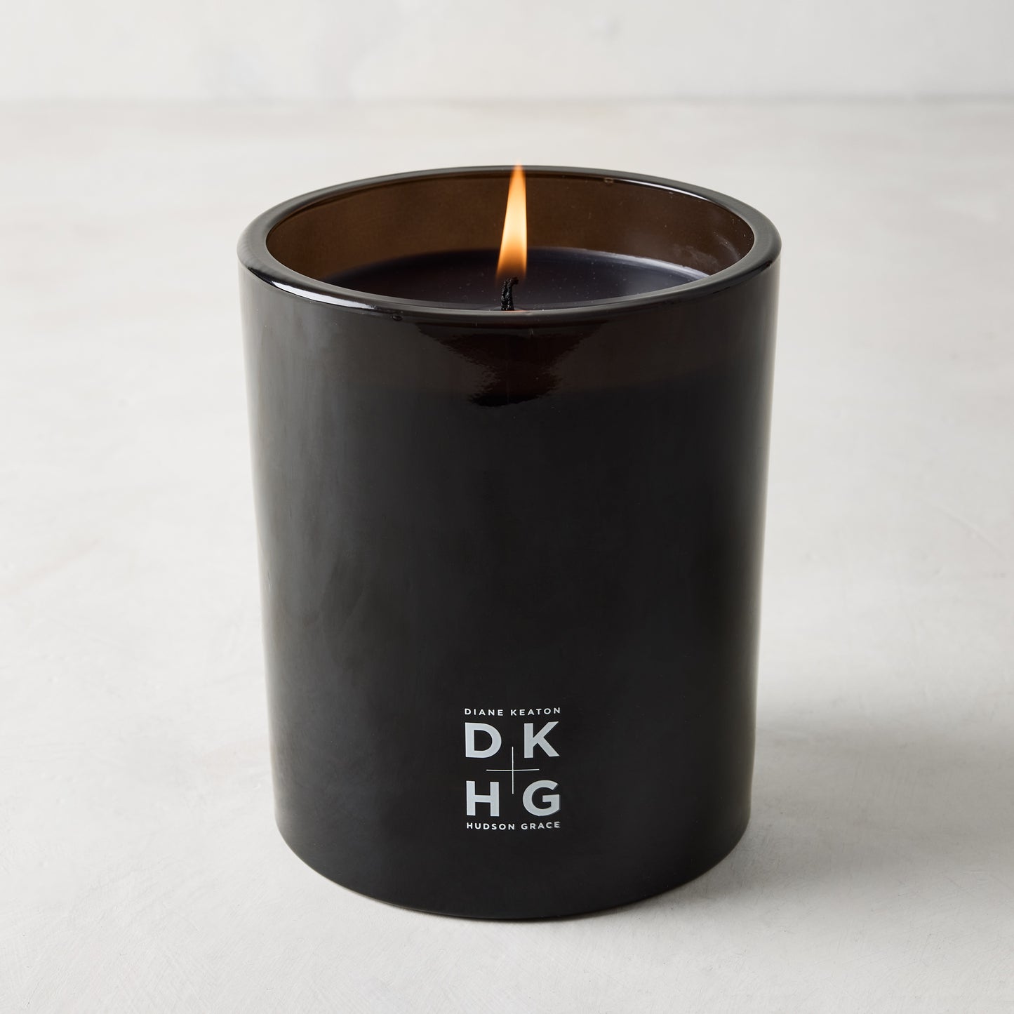 Diane Keaton x Hudson Grace "HOUSE" scented candle in a sleek black glass vessel with a burning wick.