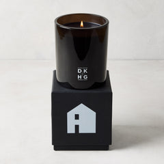 Diane Keaton x Hudson Grace "HOUSE" scented candle in a sleek black glass vessel on a black gift box with a house logo.
