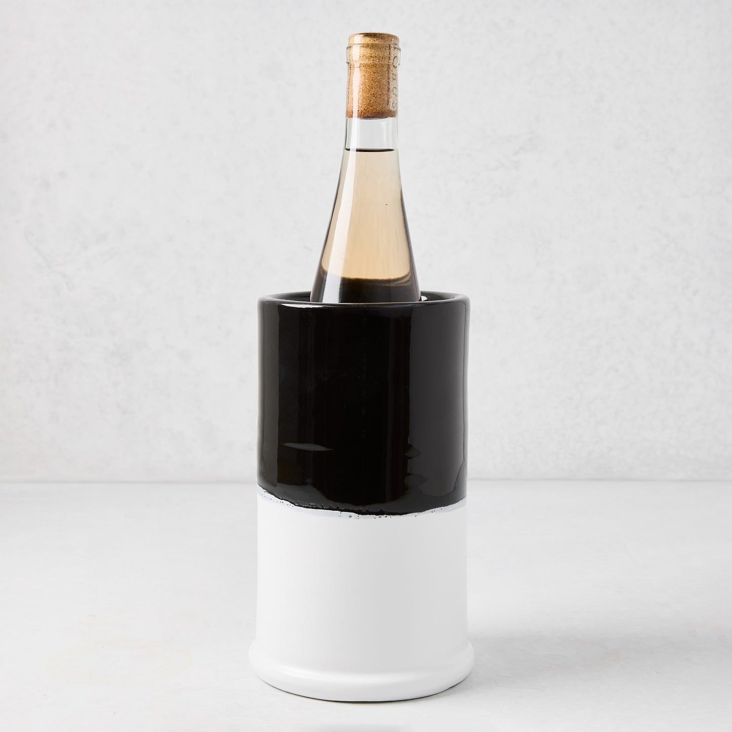 Diane Keaton + Hudson Grace black and white dipped ceramic wine chiller with a bottle of white wine.