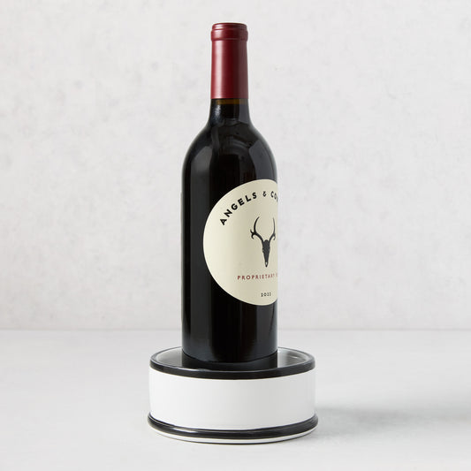 Diane Keaton + Hudson Grace black and white dipped ceramic wine coaster with a wine bottle.