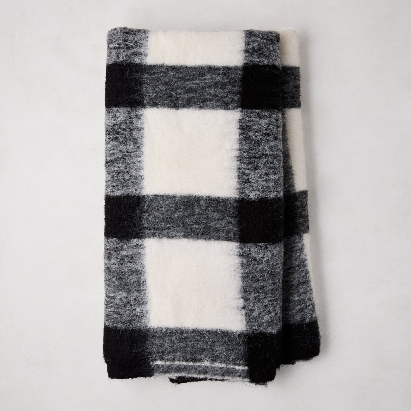 Diane Keaton + Hudson Grace black and white buffalo check alpaca throw blanket, folded.
