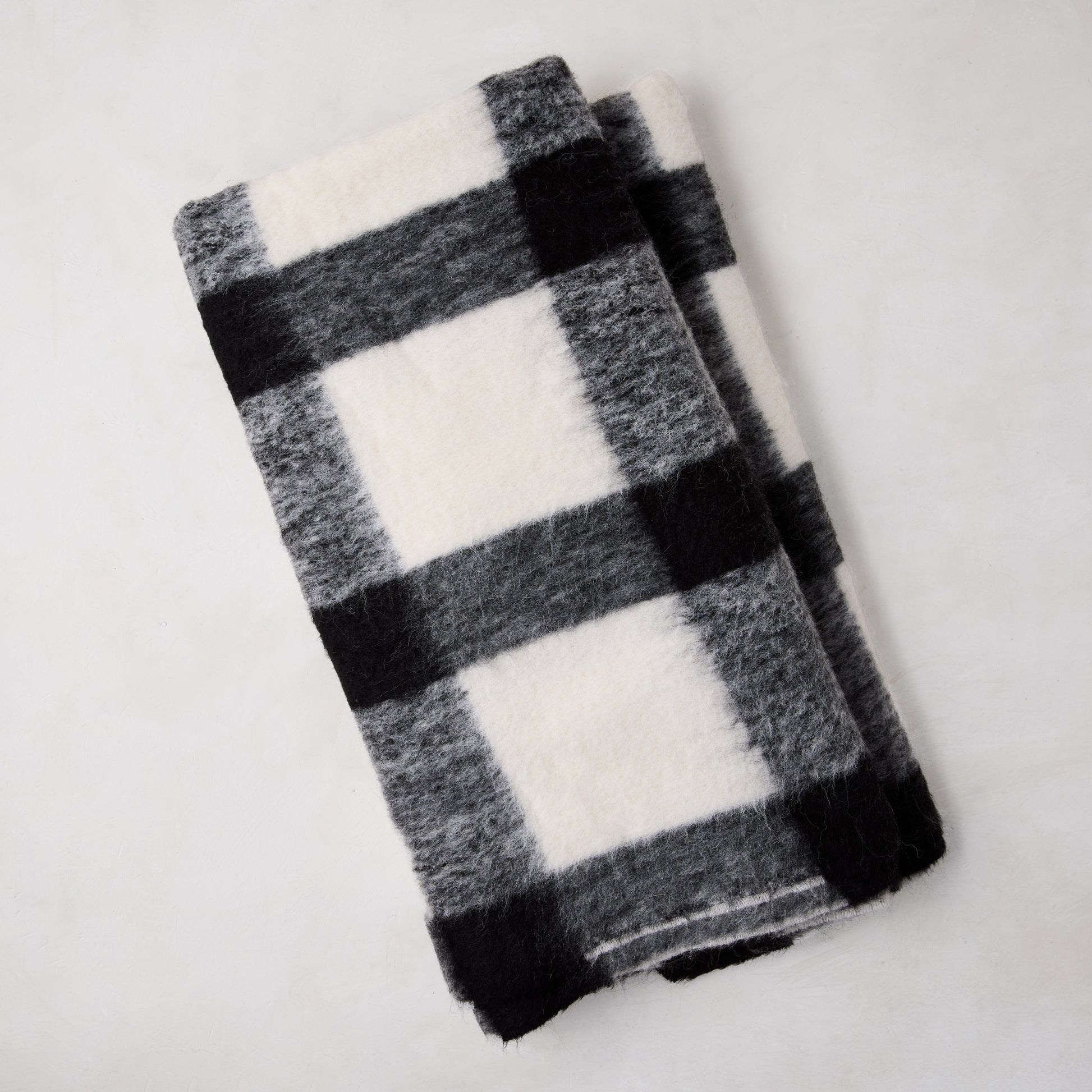Diane Keaton + Hudson Grace black and white buffalo check baby alpaca throw blanket, folded.