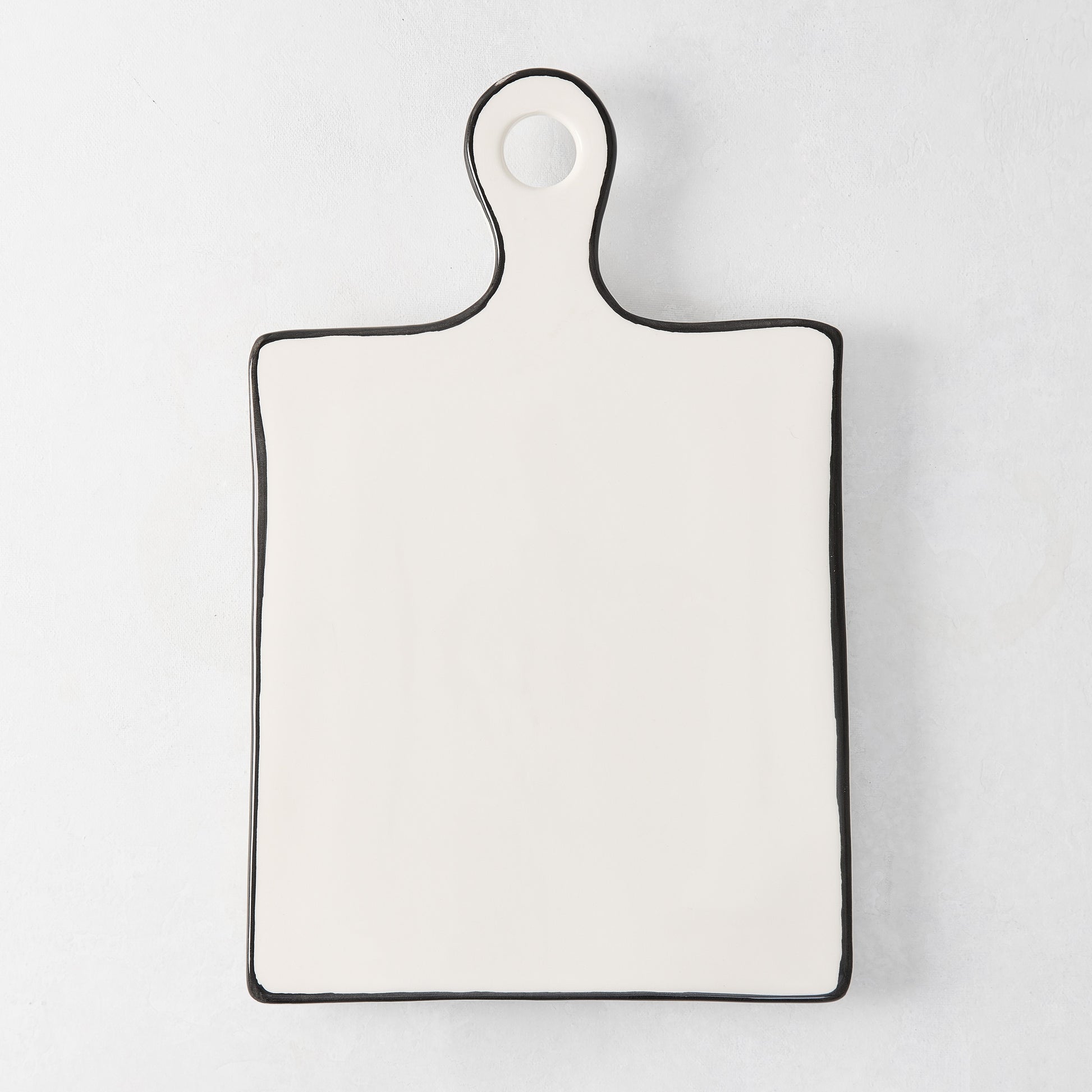 Diane Keaton + Hudson Grace ceramic cheese board with black trim and rounded handle.