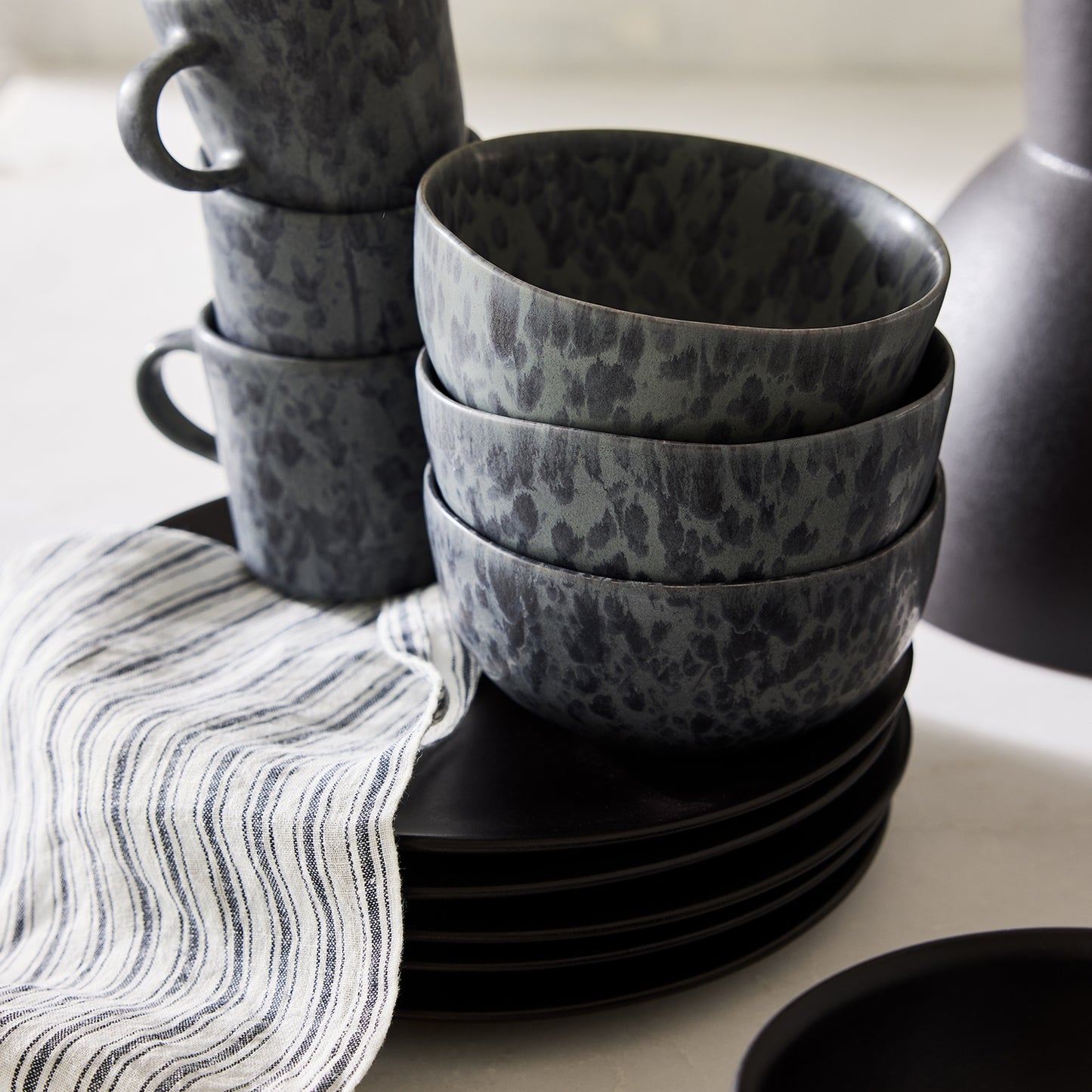 Diane Keaton + Hudson Grace Composition Splatter Stoneware Bowl, black and grey, stacked with matching dinnerware.