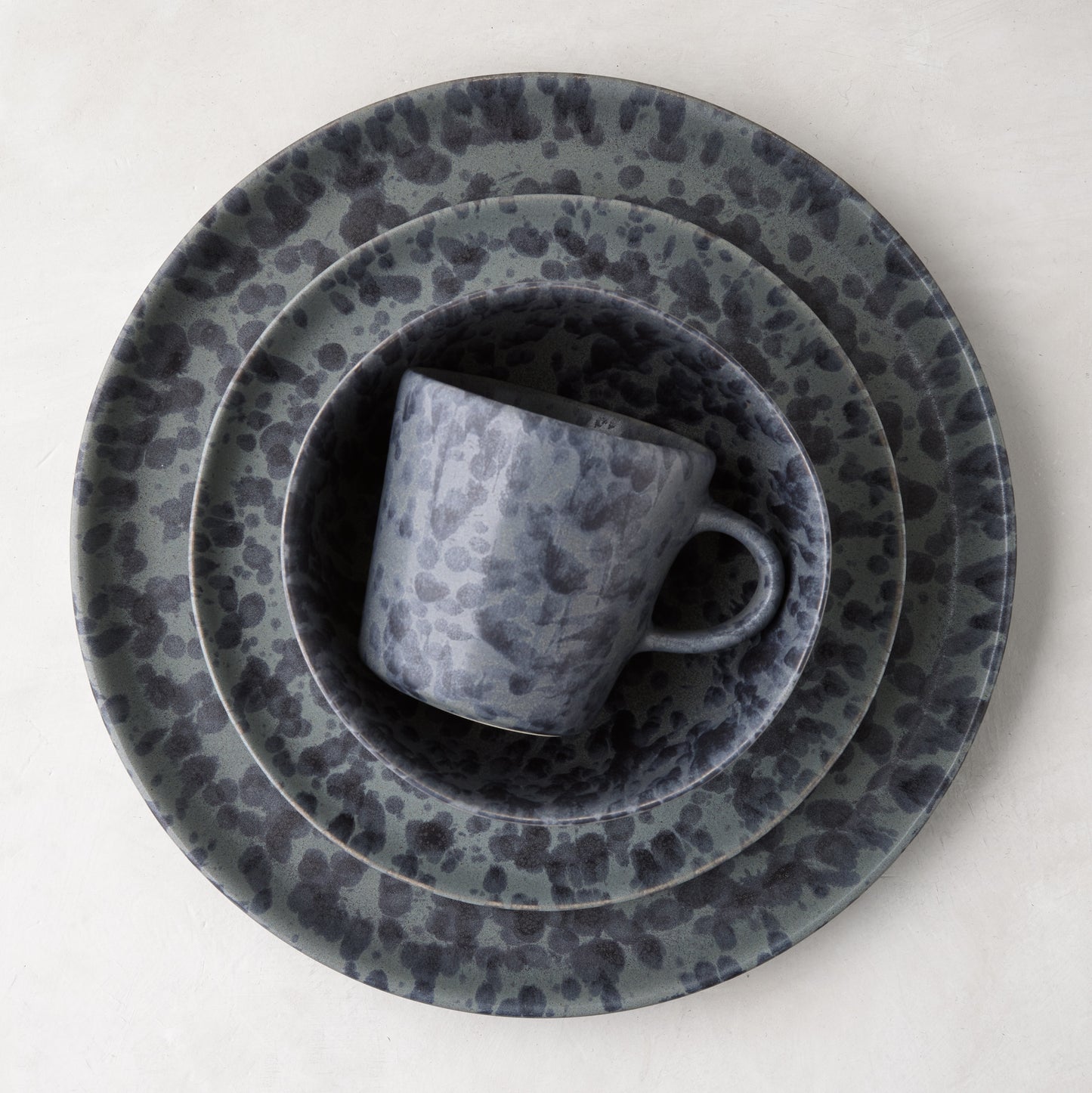 Diane Keaton + Hudson Grace black and grey splatter stoneware mug nested in matching plates.