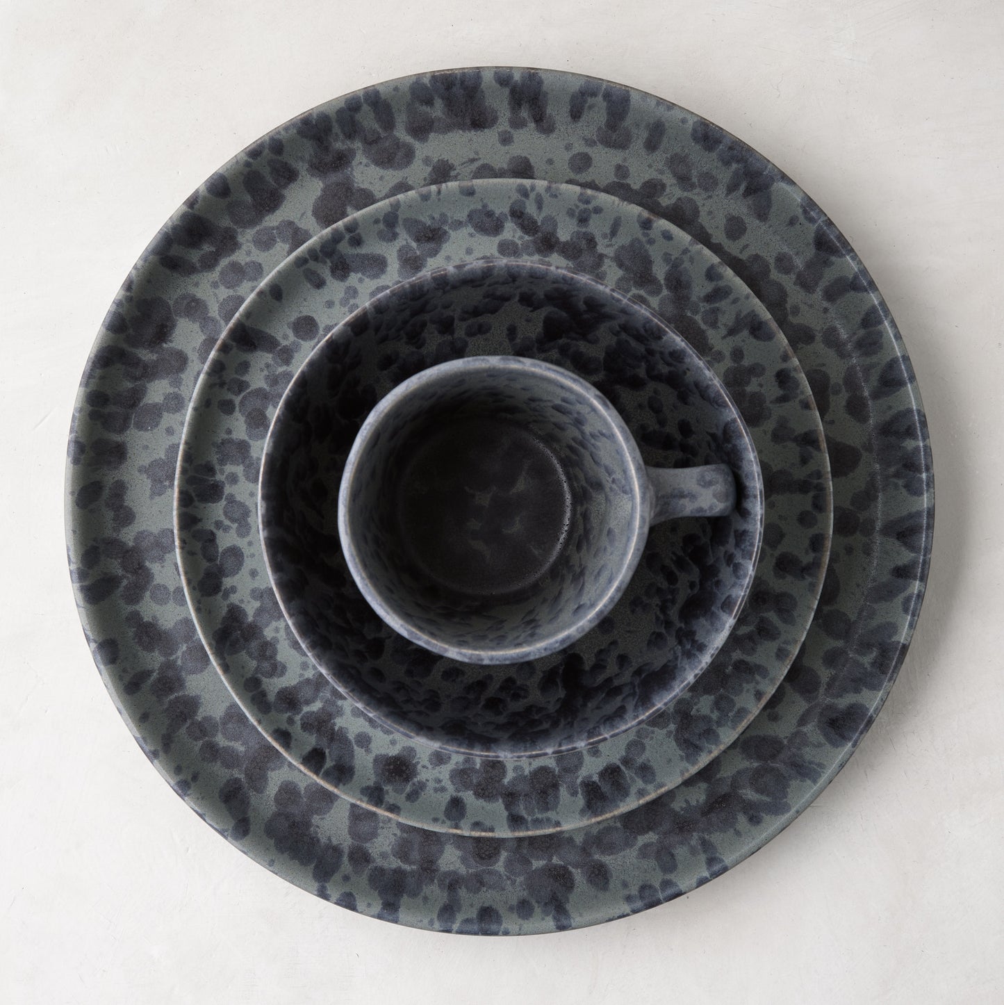 Diane Keaton + Hudson Grace black and grey splatter stoneware mug nested in matching plates.