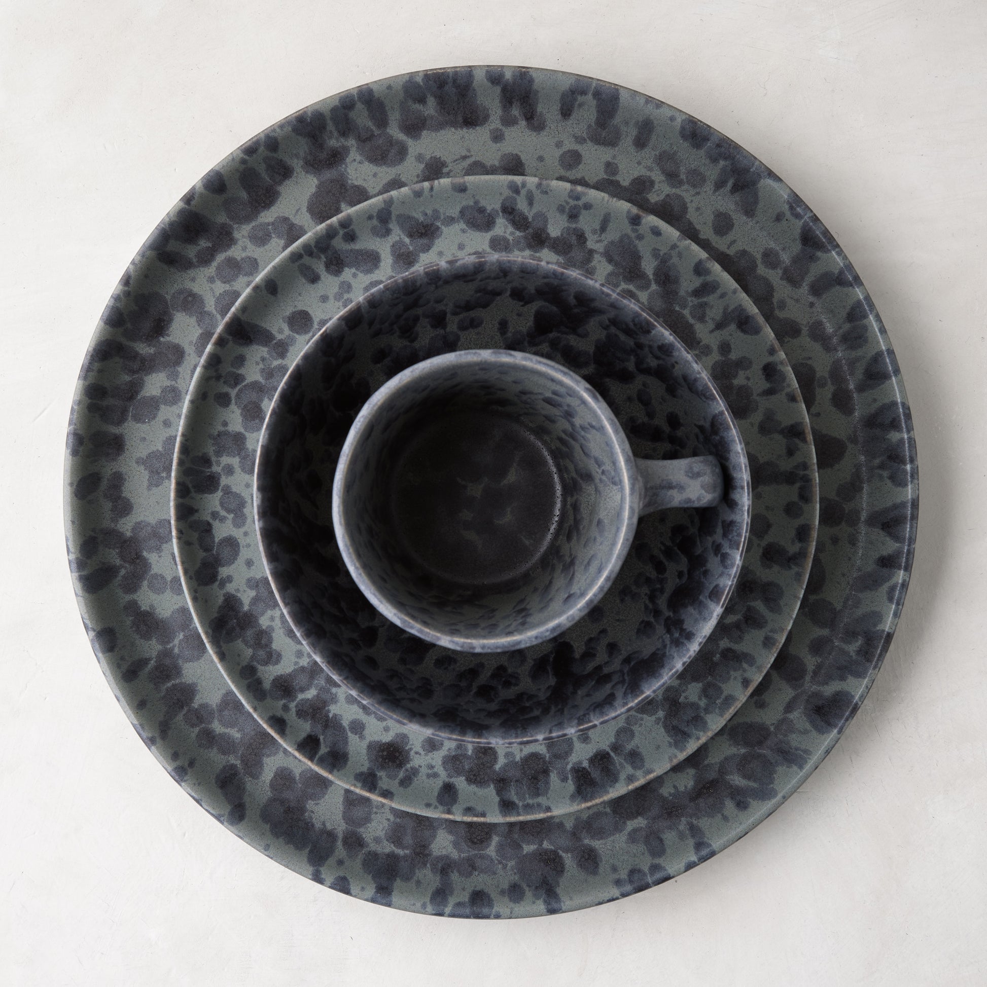 Diane Keaton + Hudson Grace black and grey splatter stoneware mug nested in matching plates.