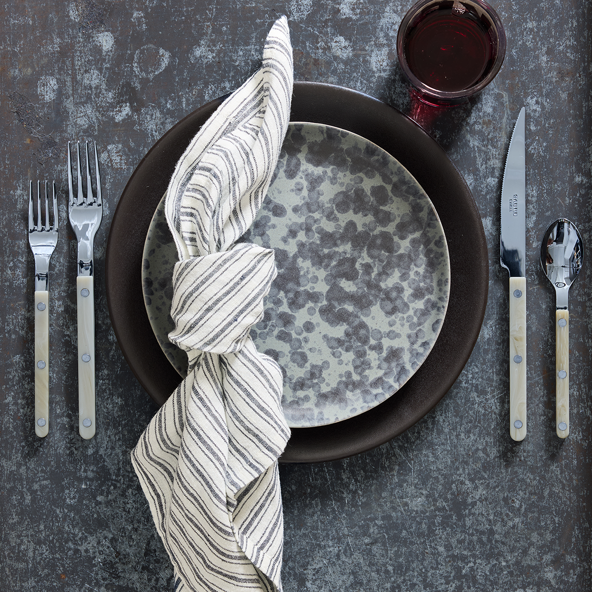 Diane Keaton x Hudson Grace stoneware salad plate with black and grey composition splatter pattern on a table setting.