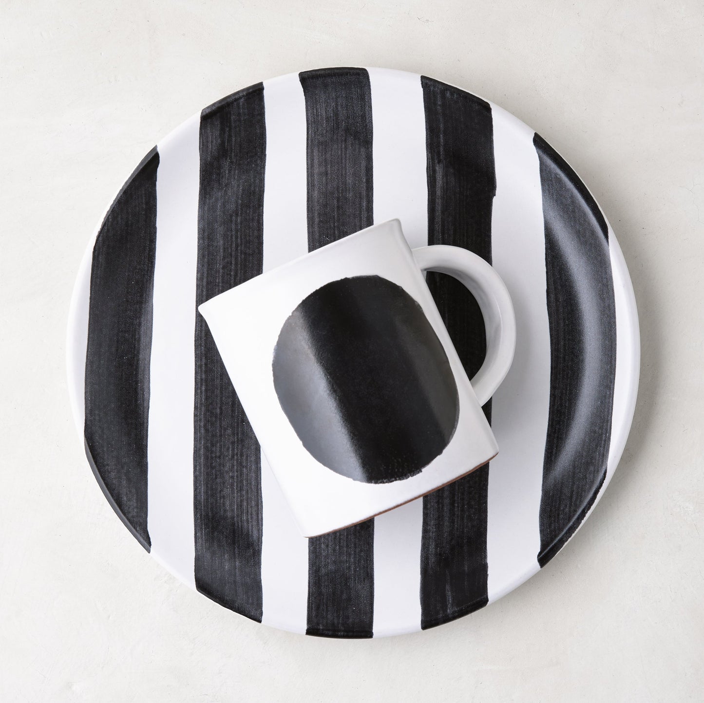 Diane Keaton + Hudson Grace Domino Dot Stoneware Mug with a bold black circle, on a striped plate.