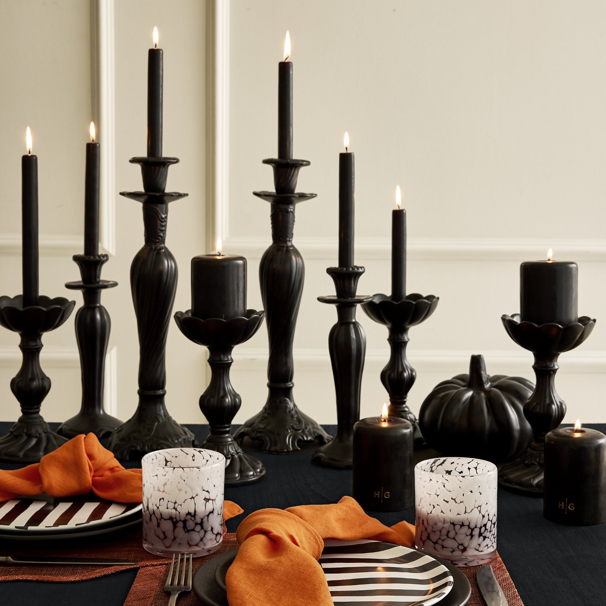 Diane Keaton + Hudson Grace black and white striped salad plate with orange napkin on a dark table setting.