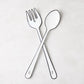 Diane Keaton + Hudson Grace white enamel serving fork and spoon with black borders, crossed.