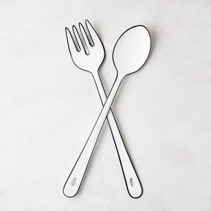 Diane Keaton + Hudson Grace white enamel serving fork and spoon with black borders, crossed.