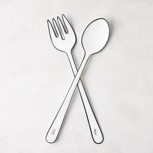 Diane Keaton + Hudson Grace white enamel serving fork and spoon with black borders, crossed.