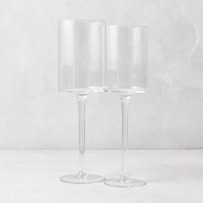 Two clear, tall Diane Keaton + Hudson Grace High Rise wine glasses on a white surface.