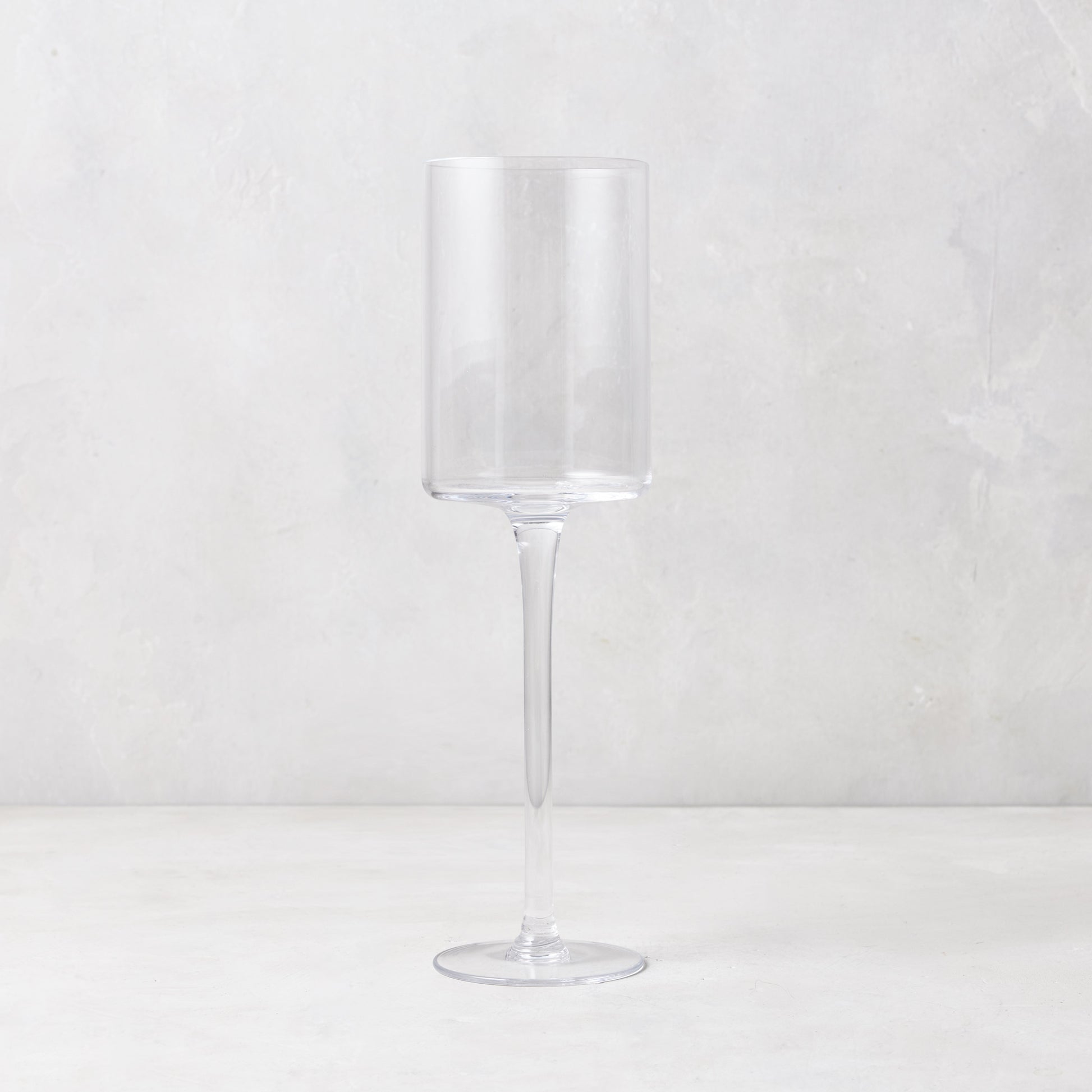 Clear, tall, straight-sided Diane Keaton + Hudson Grace High Rise Small Wine Glass on a white surface.