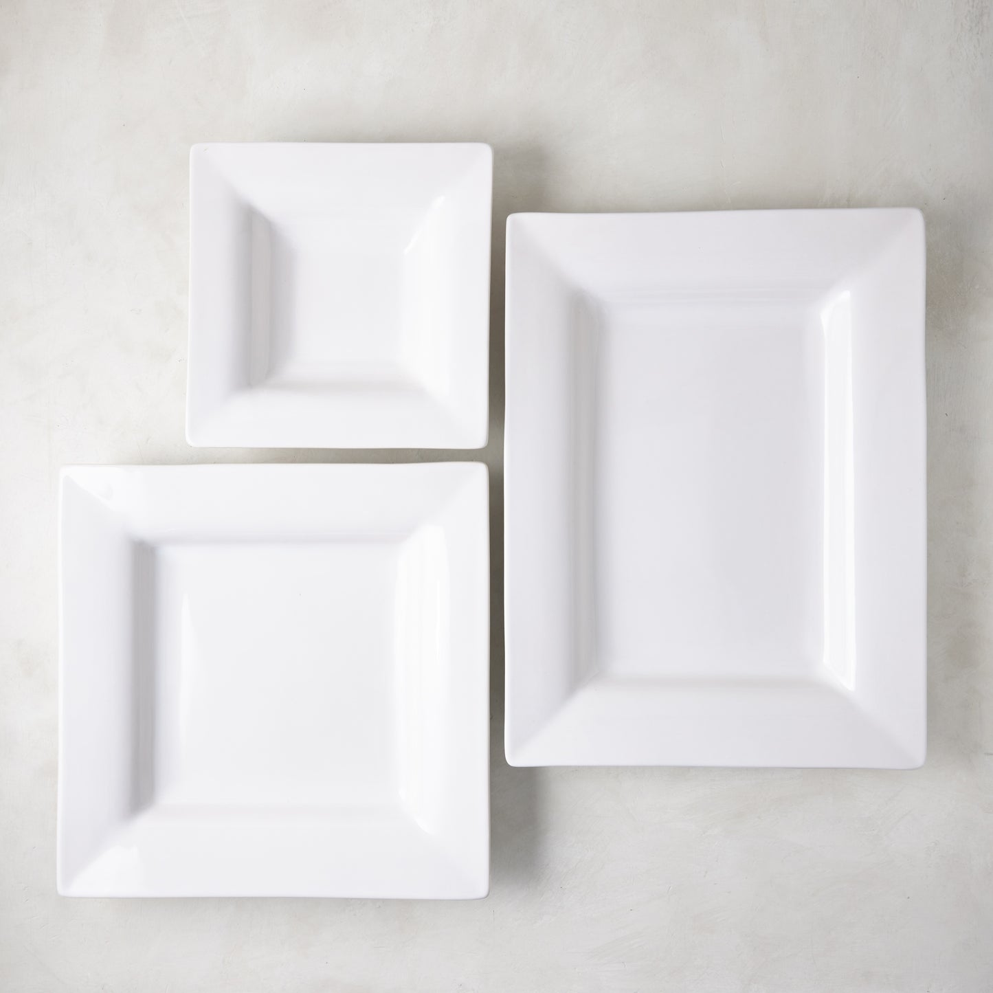 Three white ceramic square serving platters from the Diane Keaton x Hudson Grace "Keaton" collection.