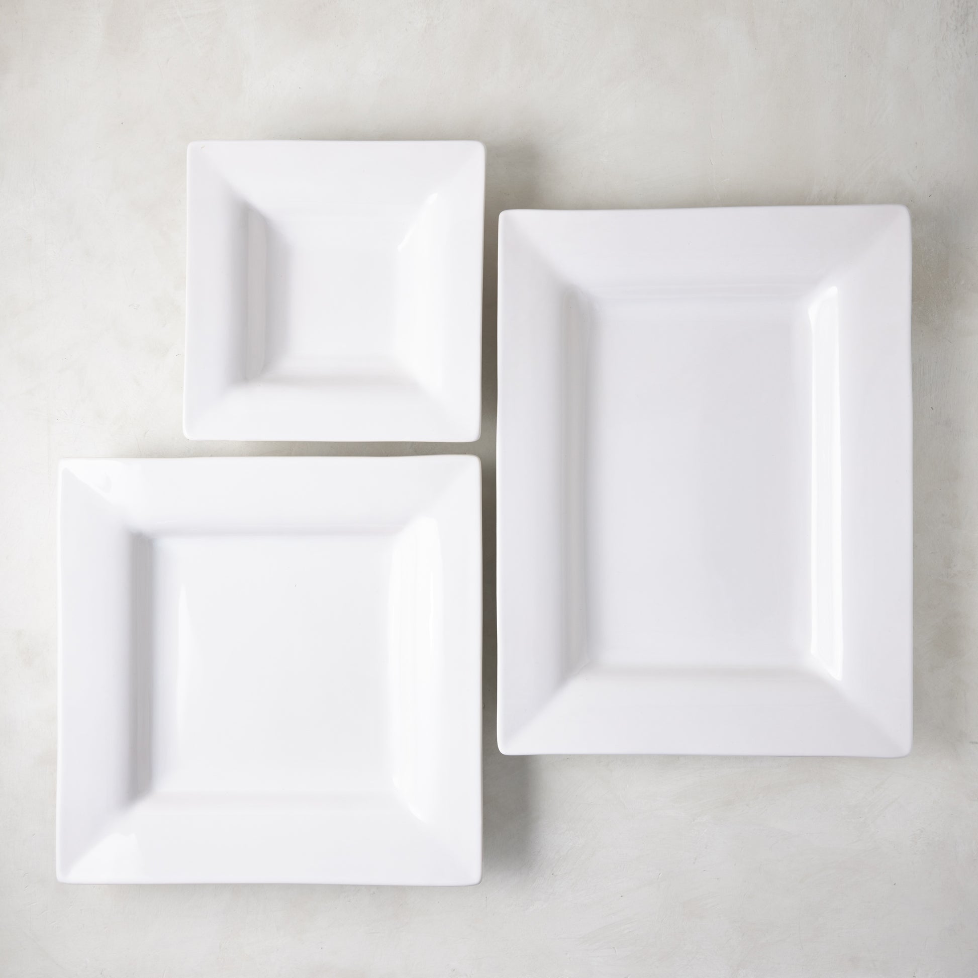 Three white ceramic square serving platters from the Diane Keaton x Hudson Grace "Keaton" collection.