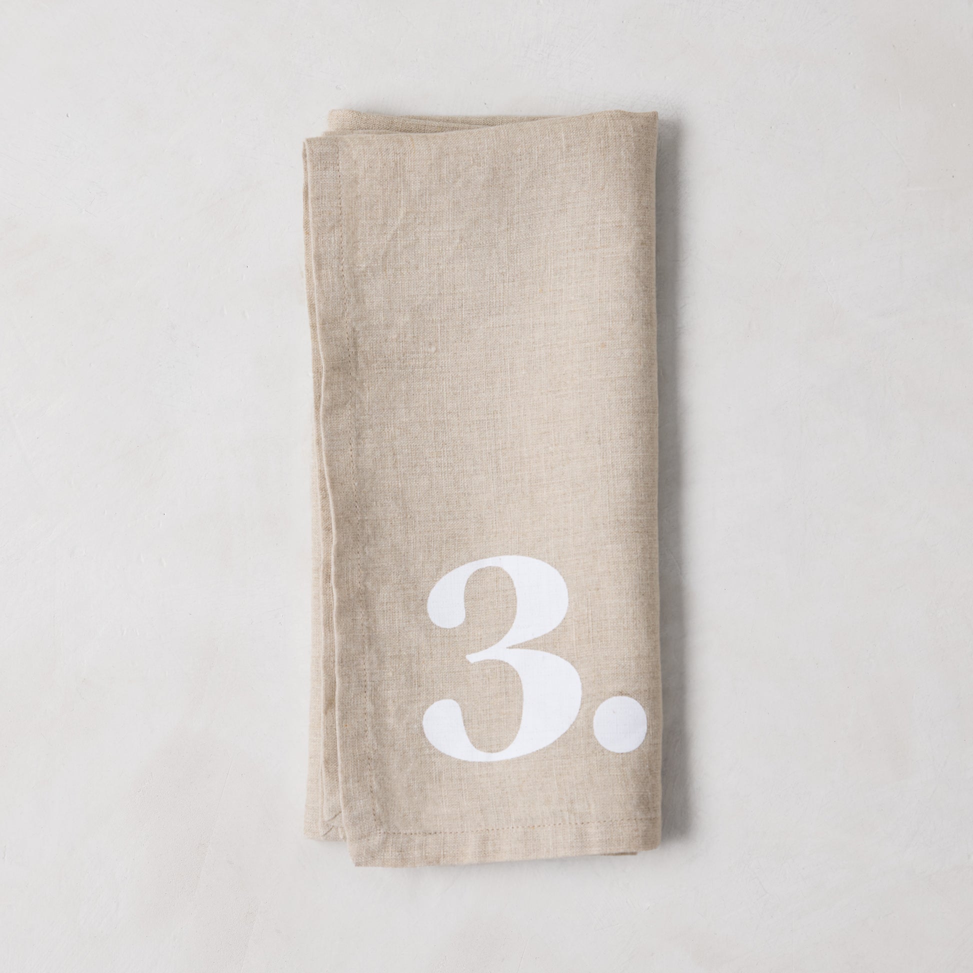 Diane Keaton + Hudson Grace khaki linen napkin with large white number 3.