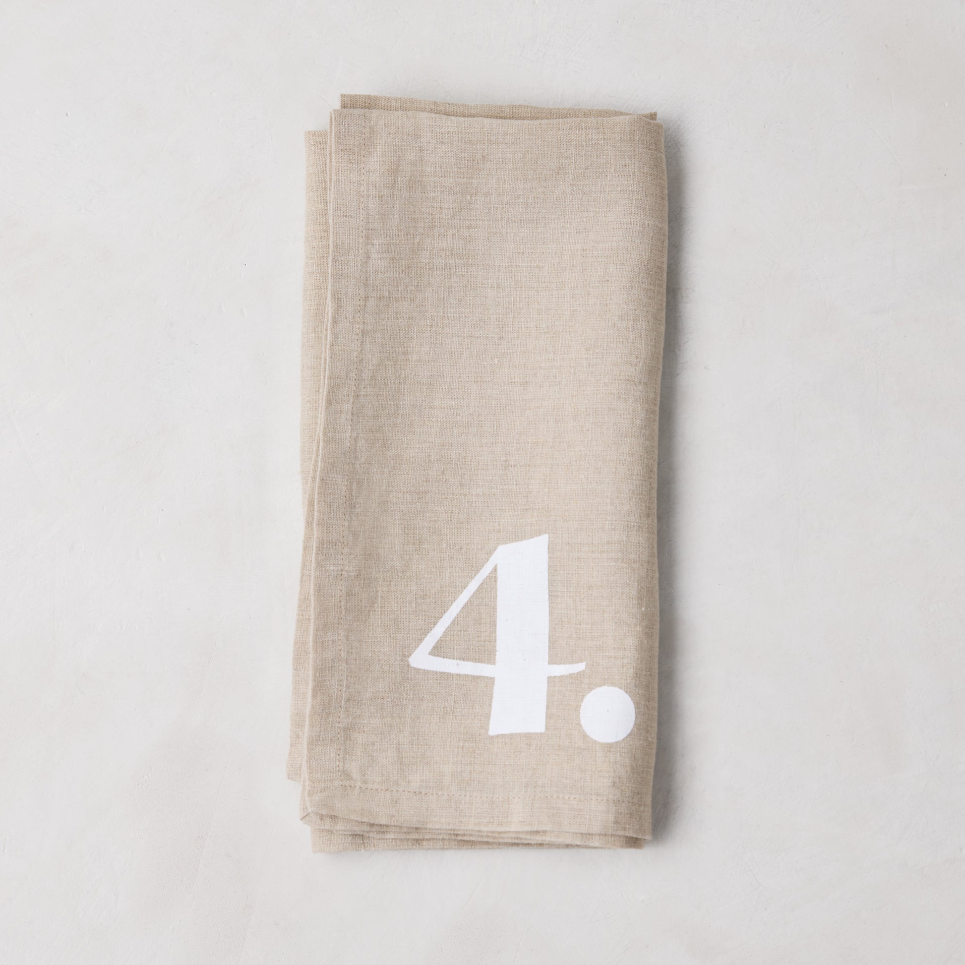 Diane Keaton + Hudson Grace Khaki Linen Numeric Napkin, folded with white number 4.