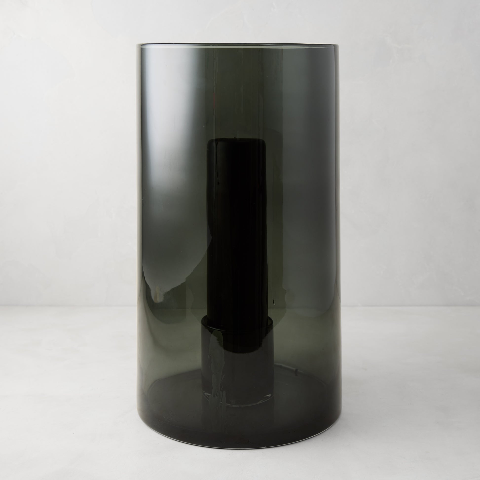 Large Diane Keaton + Hudson Grace smoke grey glass hurricane with dark pillar candle.