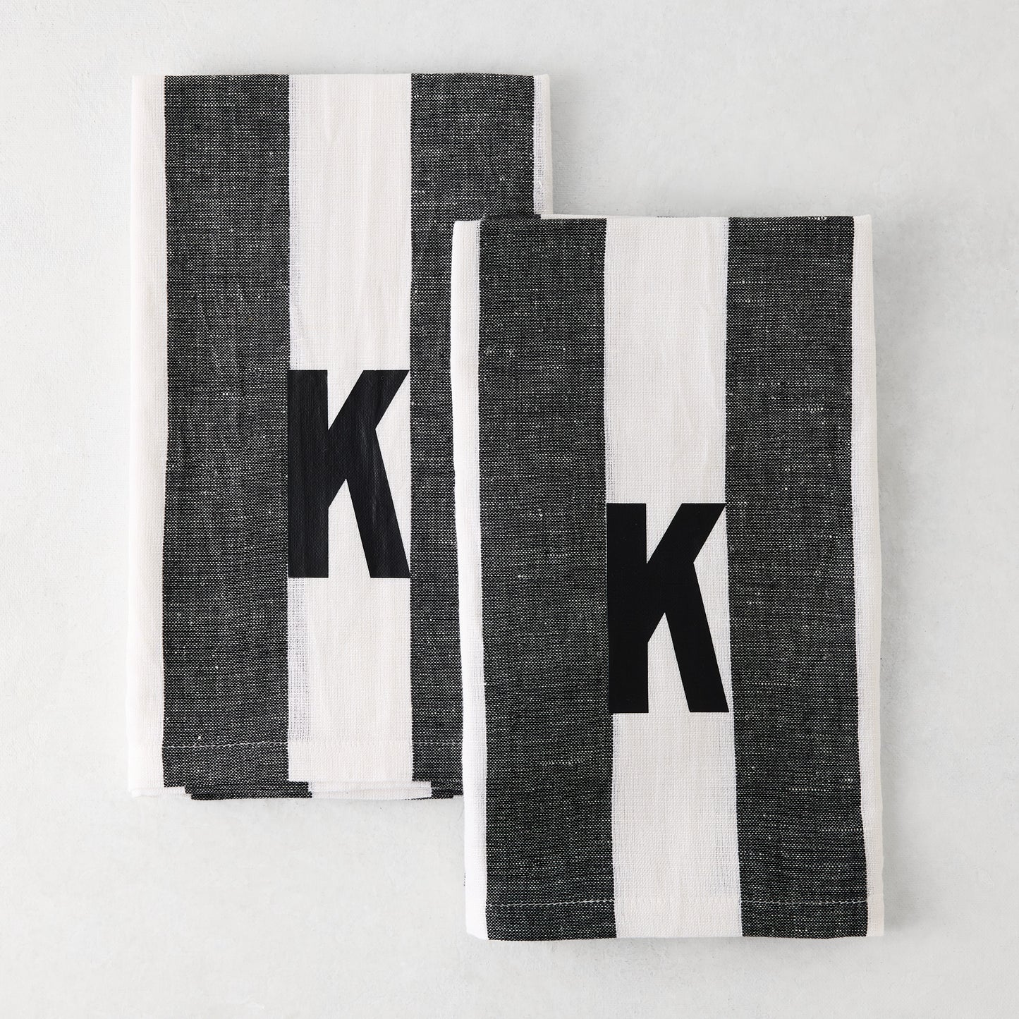 Set of 2 Diane Keaton + Hudson Grace monogrammed hand towels, grey and white striped, with black letter K.