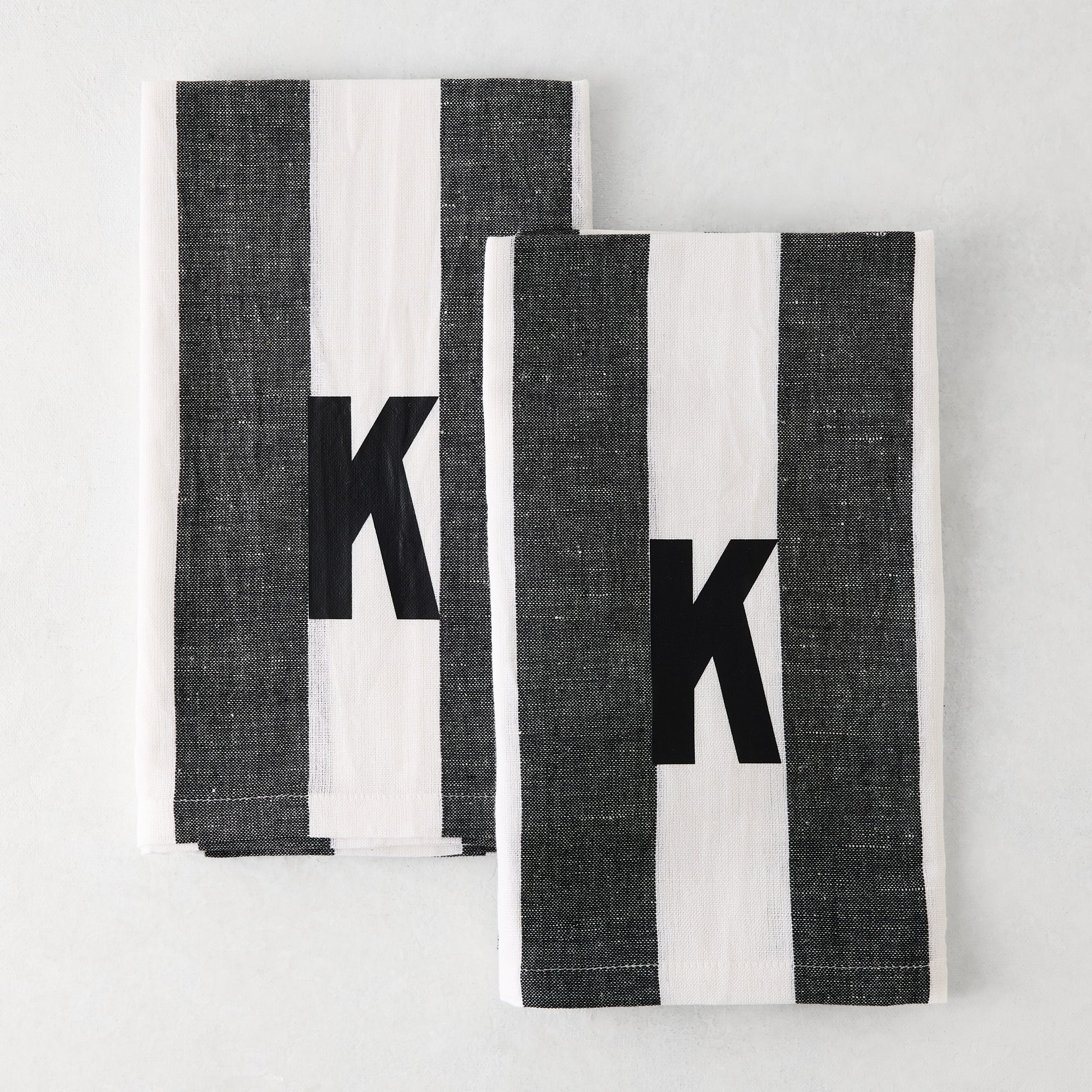 Set of 2 Diane Keaton + Hudson Grace monogrammed hand towels, grey and white striped, with black letter K.