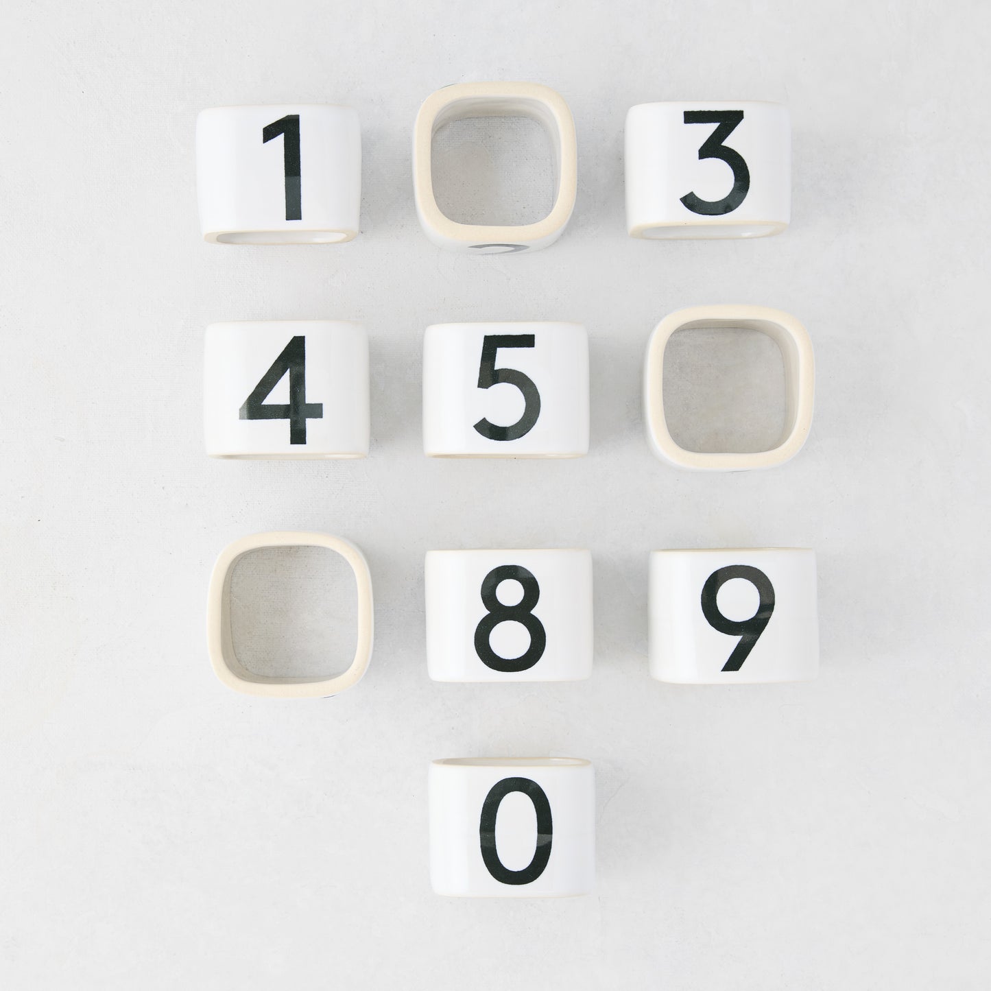 Diane Keaton + Hudson Grace white stoneware numeric napkin rings, numbered 0-9, on a light surface.