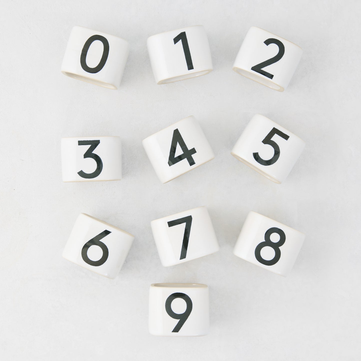 White stoneware napkin rings with black numbers 0-9 from the Diane Keaton + Hudson Grace Collection.