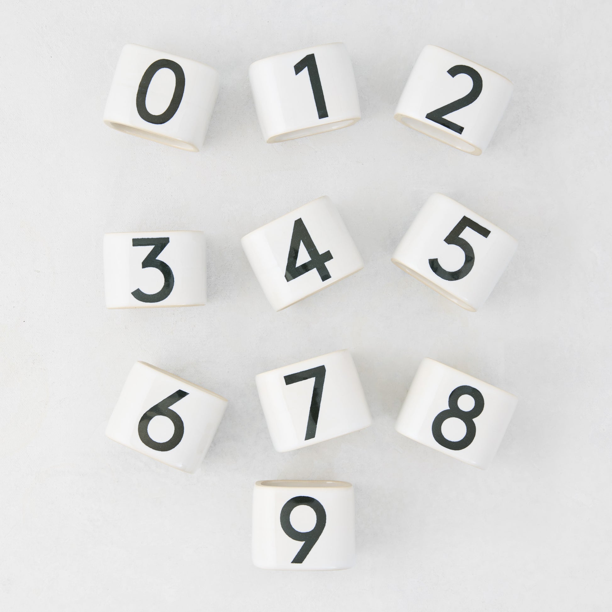White stoneware napkin rings with black numbers 0-9 from the Diane Keaton + Hudson Grace Collection.
