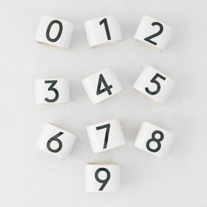 White stoneware napkin rings with black numbers 0-9 from the Diane Keaton + Hudson Grace Collection.