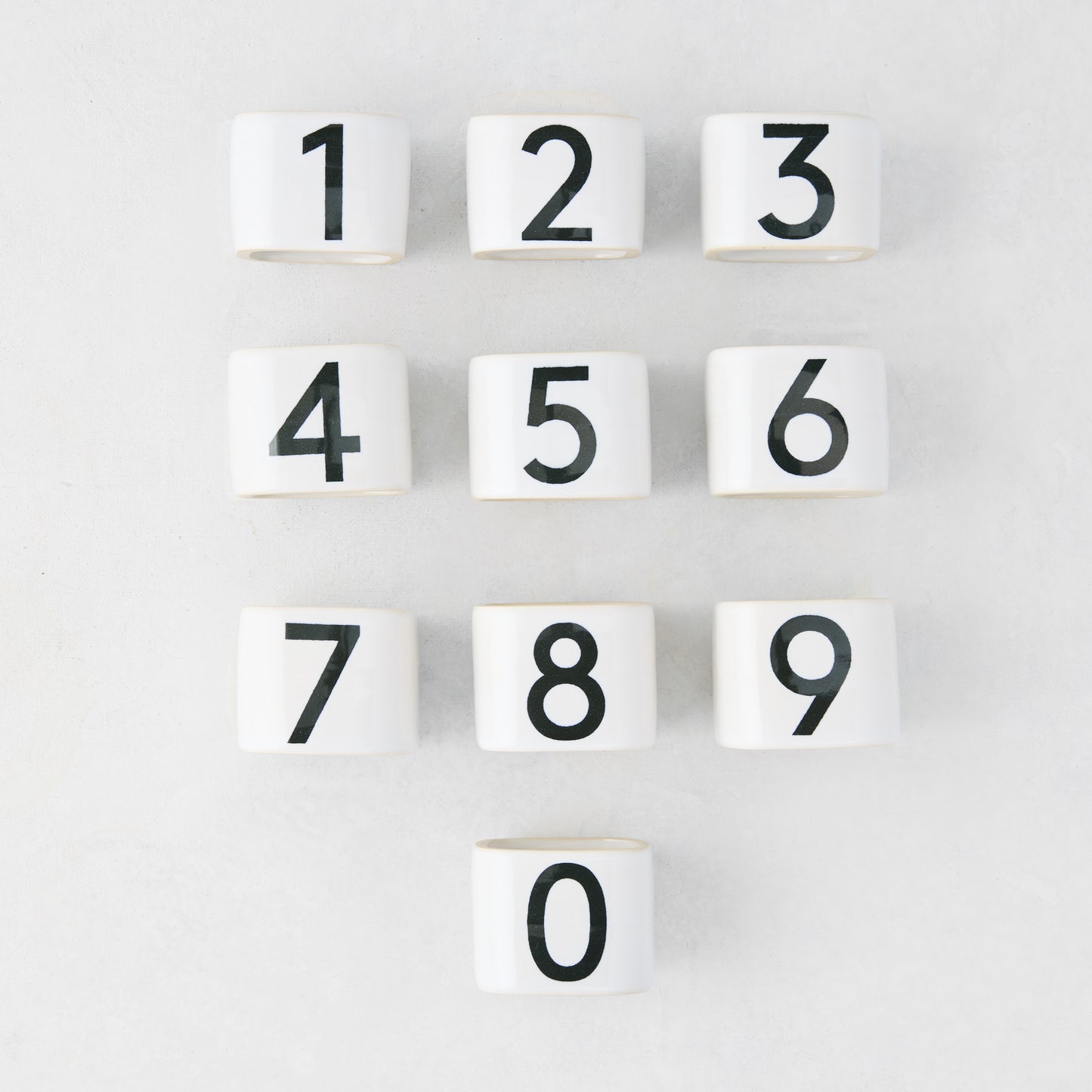 Set of 10 white stoneware napkin rings with black numbers 0-9, from the Diane Keaton + Hudson Grace Collection.