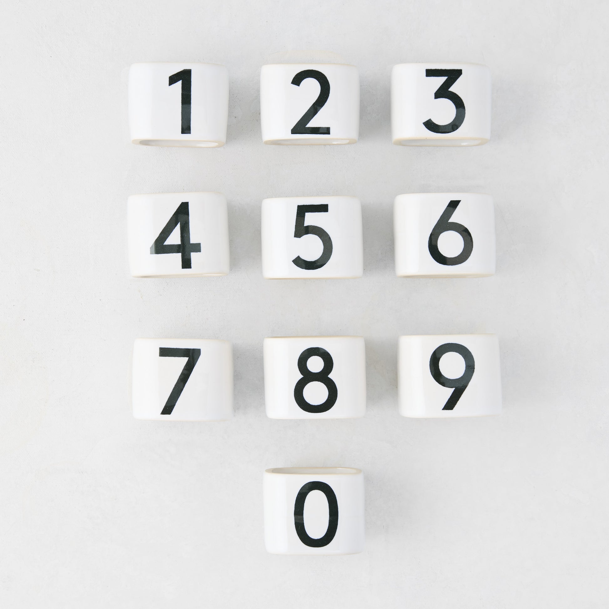 Set of 10 white stoneware napkin rings with black numbers 0-9, from the Diane Keaton + Hudson Grace Collection.