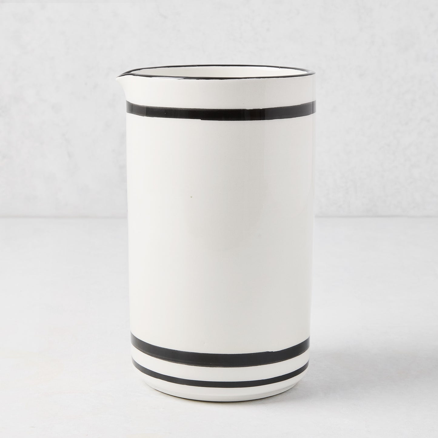 Diane Keaton + Hudson Grace white ceramic wine carafe with black stripes and rim.