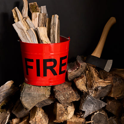 Diane Keaton + Hudson Grace Flame Red galvanized steel "FIRE" bucket with logs, next to an axe and woodpile.