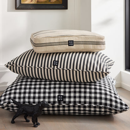 Diane Keaton x Hudson Grace dog bed stack: natural stripe, black stripe, black gingham, with "Reggie" cast iron dog.