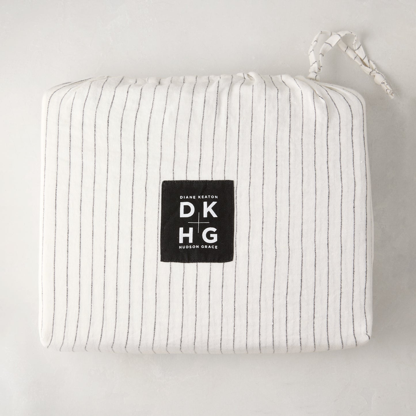Diane Keaton + Hudson Grace Shirting Stripe Linen Duvet Cover, folded in its striped linen bag with logo.